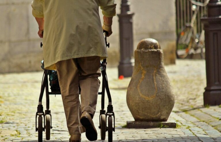 Seniorin zu Fuß unterwegs mit dem Rollator: Bewegungsangebote sorgen dafür, dass Menschen im Alter länger mobil bleiben.